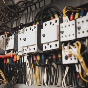 Electricity and electrical maintenance service, Engineer hand holding AC multimeter checking electric current voltage at circuit breaker terminal and cable wiring main power distribution board.